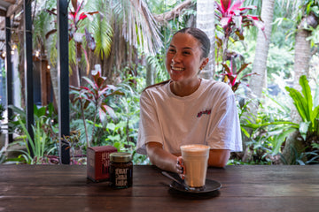 Woman enjoying Vallentine & Co Guaraná Latte in a tropical Byron Bay setting